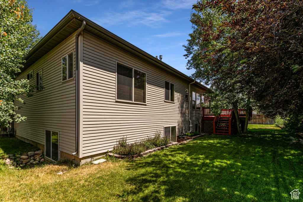 View of property exterior with a deck and a lawn