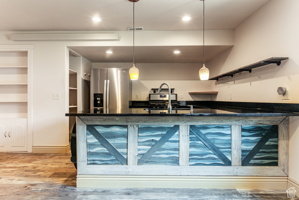 Kitchen with hardwood / wood-style floors, stainless steel fridge, decorative light fixtures, stove, and sink