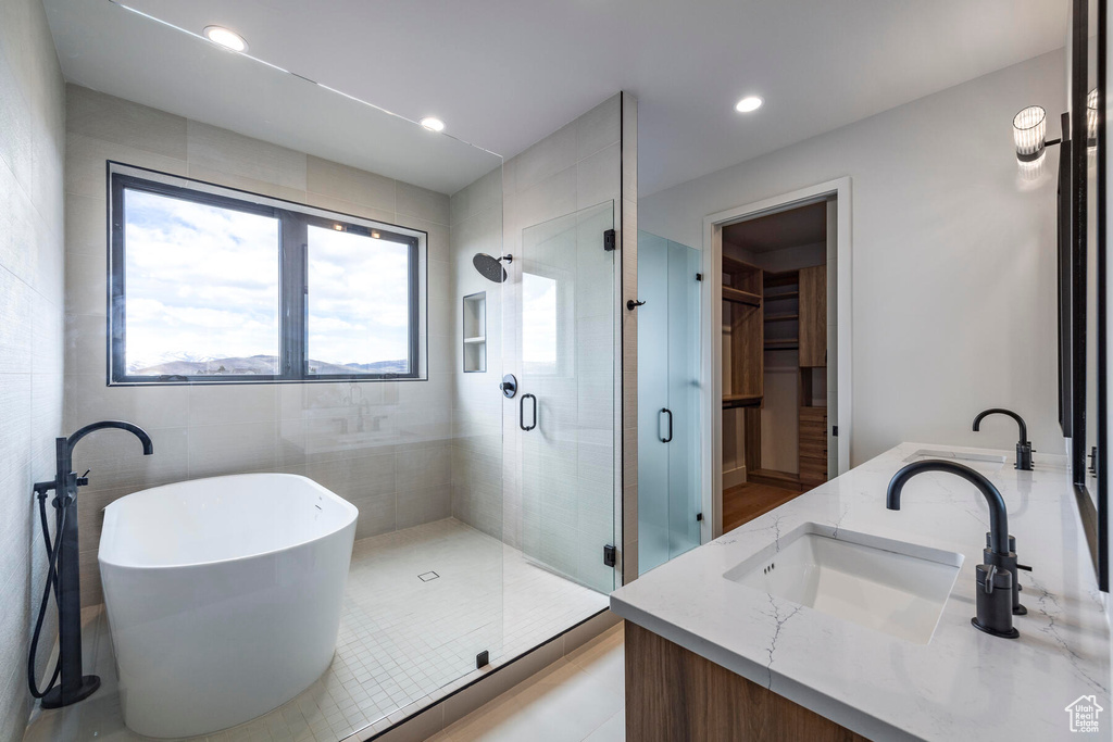 Bathroom featuring vanity, shower with separate bathtub, and tile walls