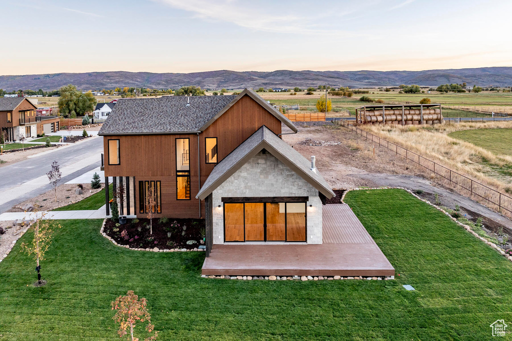 Back house at dusk featuring a yard and a mountain view