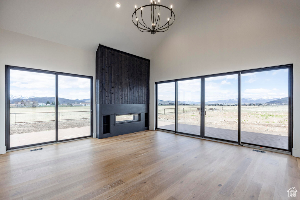 Unfurnished living room with high vaulted ceiling, light wood-type flooring, and a wealth of natural light