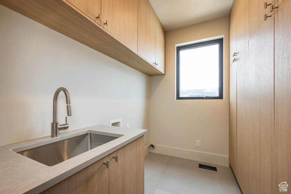 Laundry area featuring cabinets, light tile patterned flooring, hookup for a washing machine, and sink