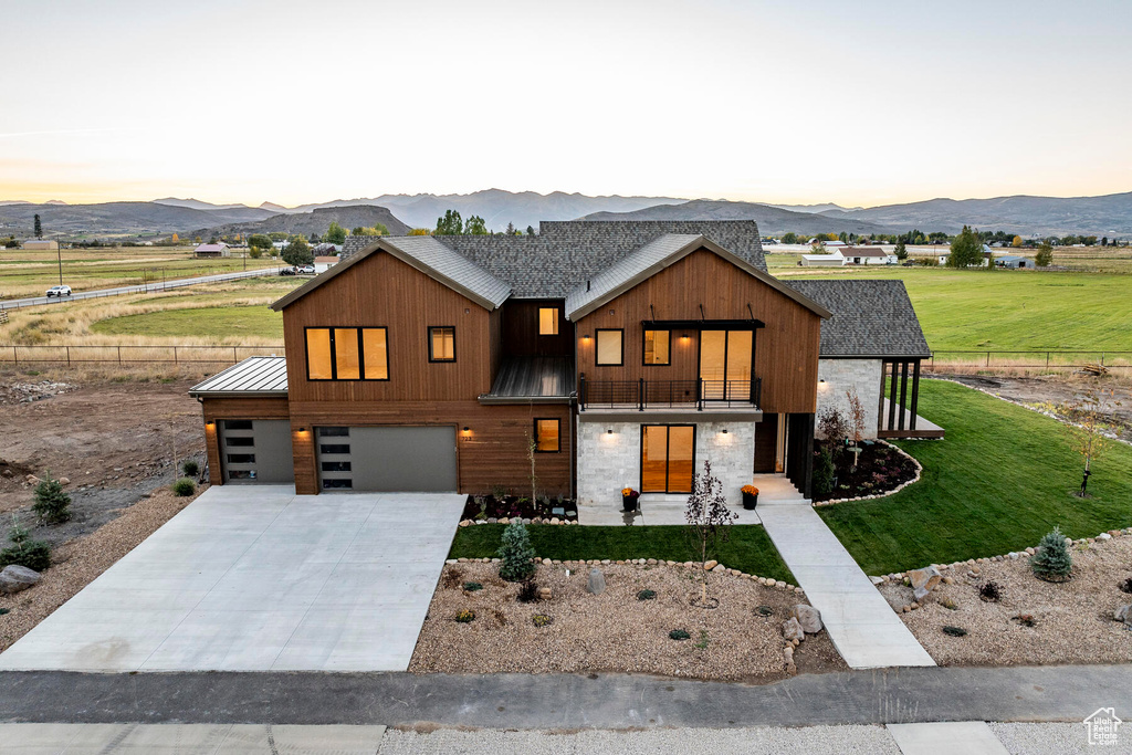 View of front of property with a mountain view, a garage, a lawn, and a balcony