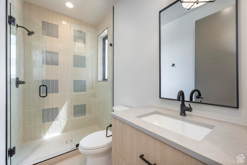 Bathroom with toilet, vanity, and a shower with shower door