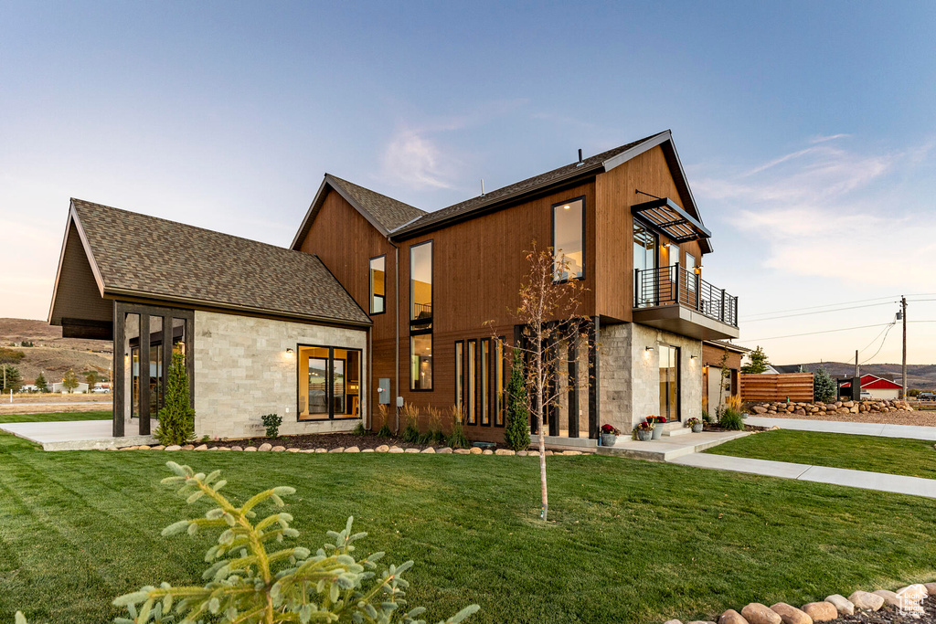 Modern home with a front yard and a balcony