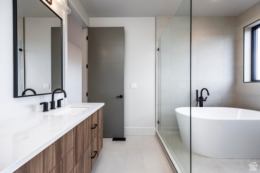 Bathroom featuring tile patterned flooring, shower with separate bathtub, and vanity