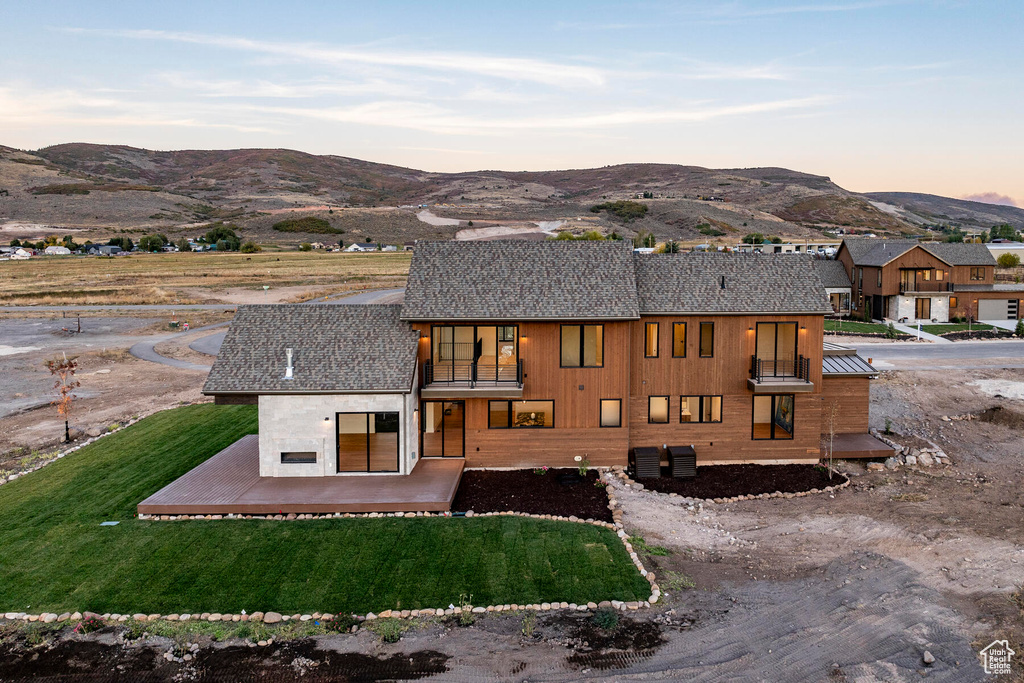 Back house at dusk with a yard and a mountain view