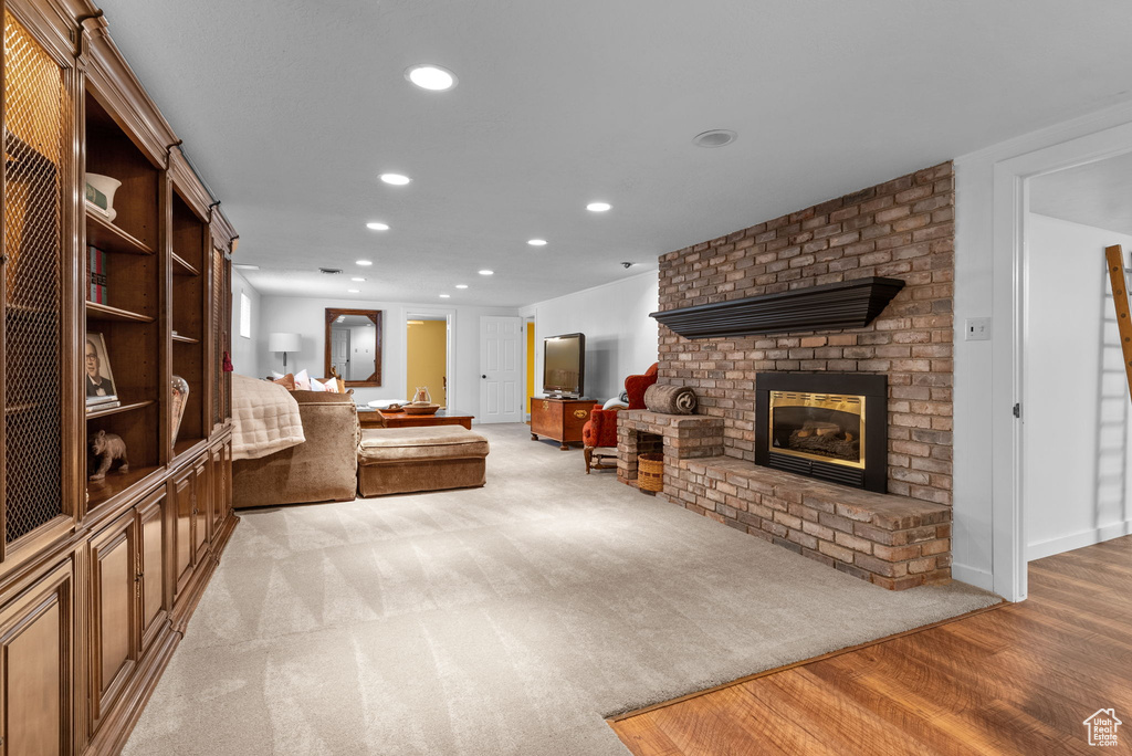 Living room with brick wall, a brick fireplace, and light hardwood / wood-style floors