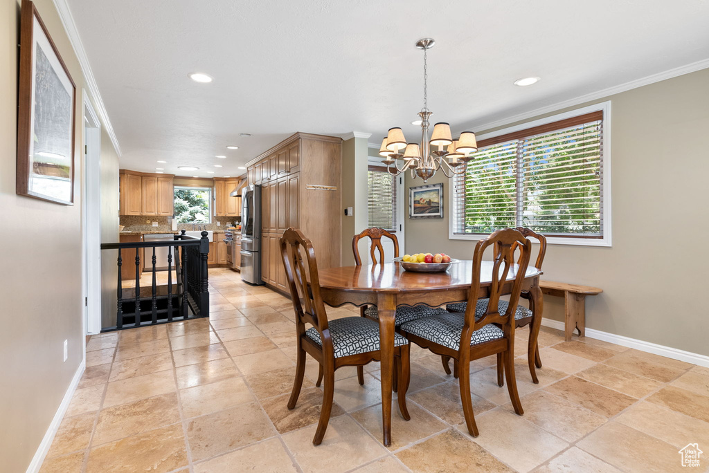 Dining area featuring a notable chandelier, light tile patterned floors, and crown molding