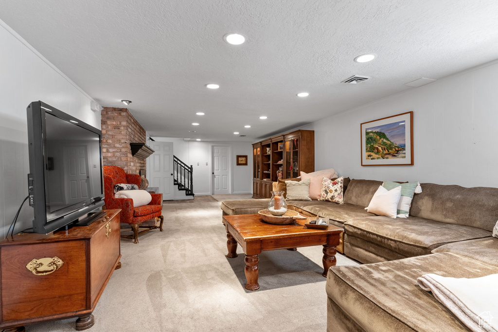 Living room with brick wall, light carpet, and a textured ceiling