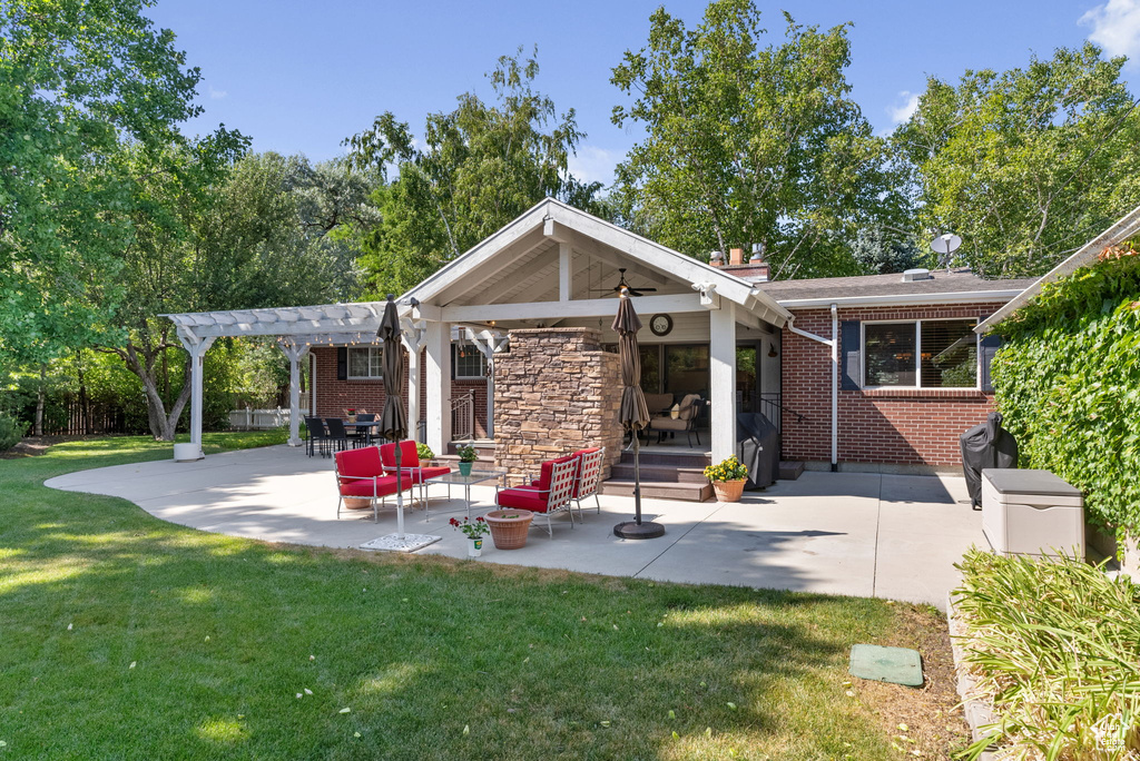 Rear view of house featuring a pergola, a patio, and a lawn