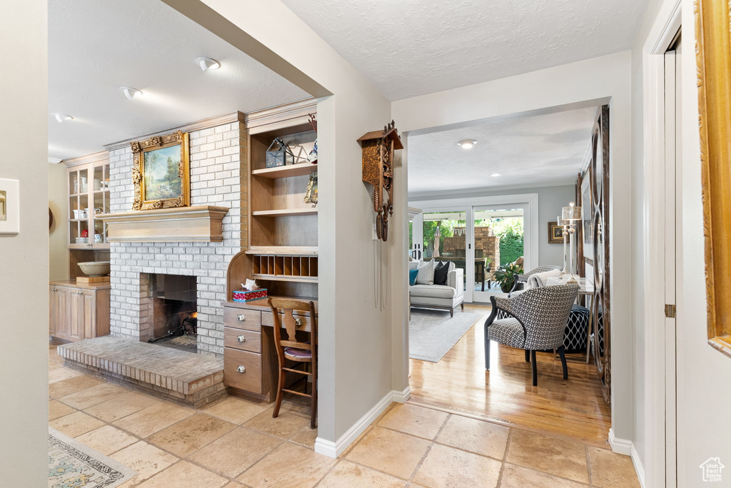 Corridor featuring brick wall, built in shelves, light hardwood / wood-style floors, and a textured ceiling