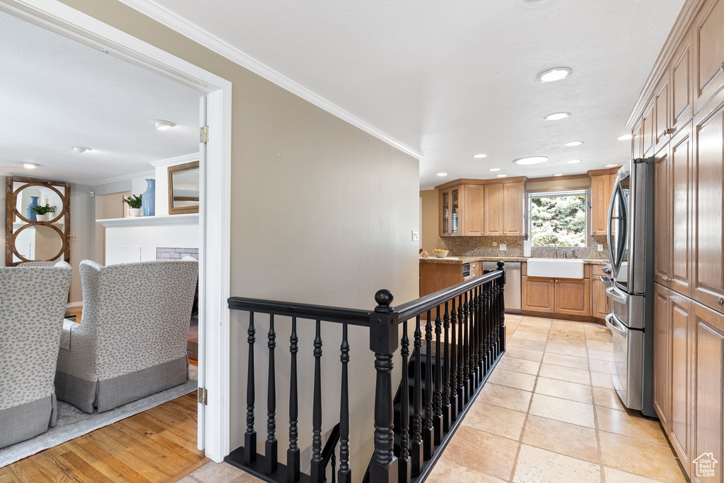 Kitchen featuring decorative backsplash, crown molding, sink, stainless steel fridge, and light hardwood / wood-style floors