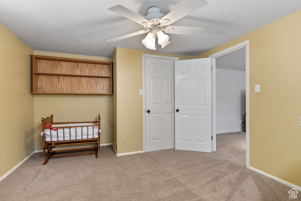 Bedroom with light colored carpet, a closet, and ceiling fan