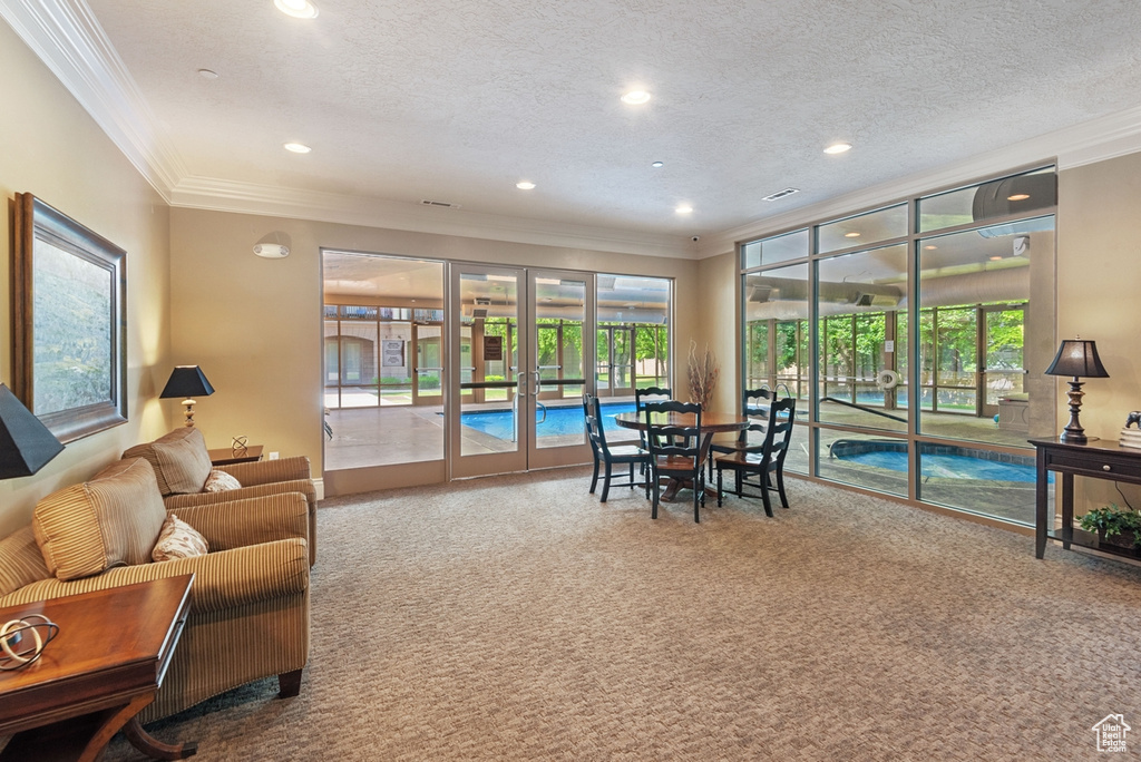 Living room with french doors, a textured ceiling, carpet floors, and crown molding