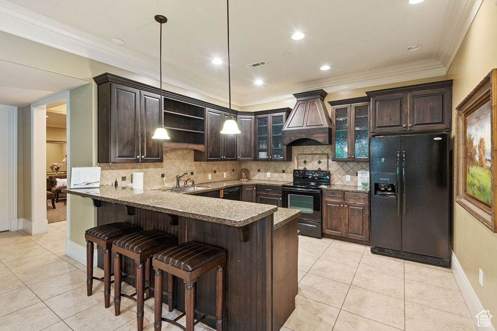 Kitchen featuring custom range hood, kitchen peninsula, backsplash, and black appliances