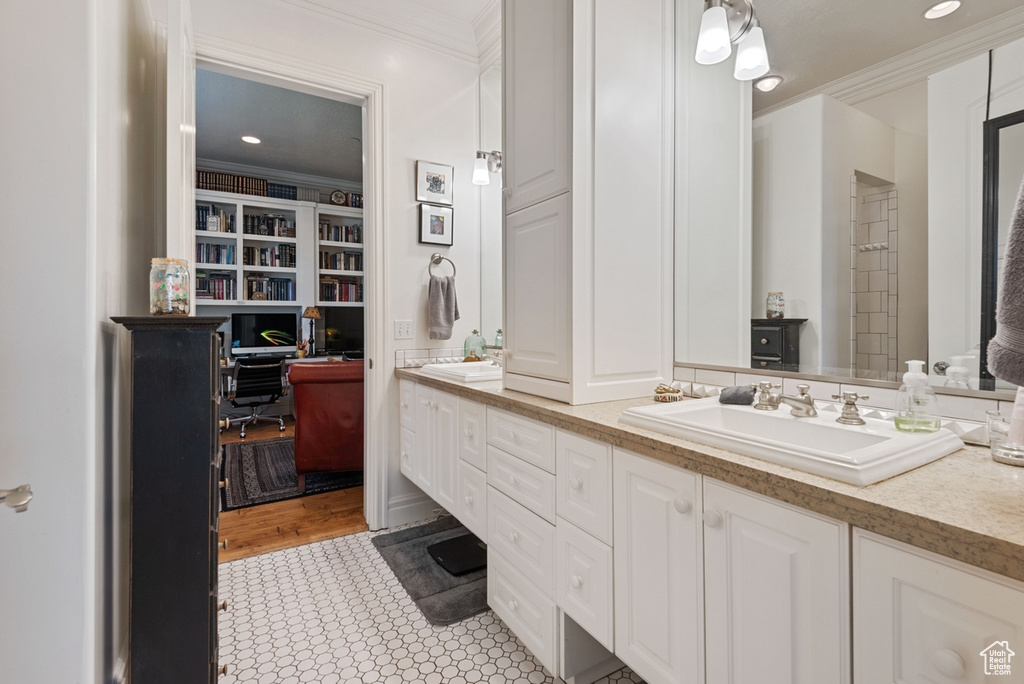 Bathroom featuring built in features, ornamental molding, hardwood / wood-style flooring, and vanity