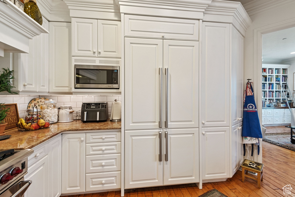 Kitchen featuring crown molding, white cabinetry, light wood-type flooring, appliances with stainless steel finishes, and backsplash