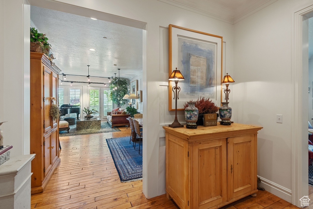 Hall with ornamental molding and light hardwood / wood-style flooring