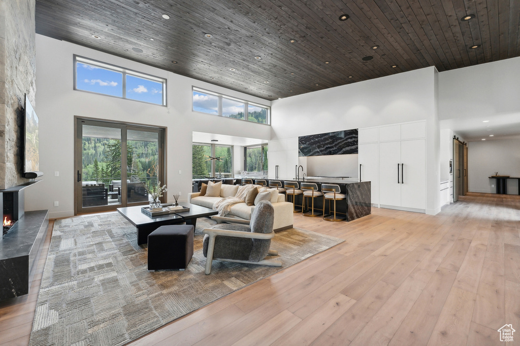 Living room featuring wood ceiling, a high ceiling, and light hardwood / wood-style floors