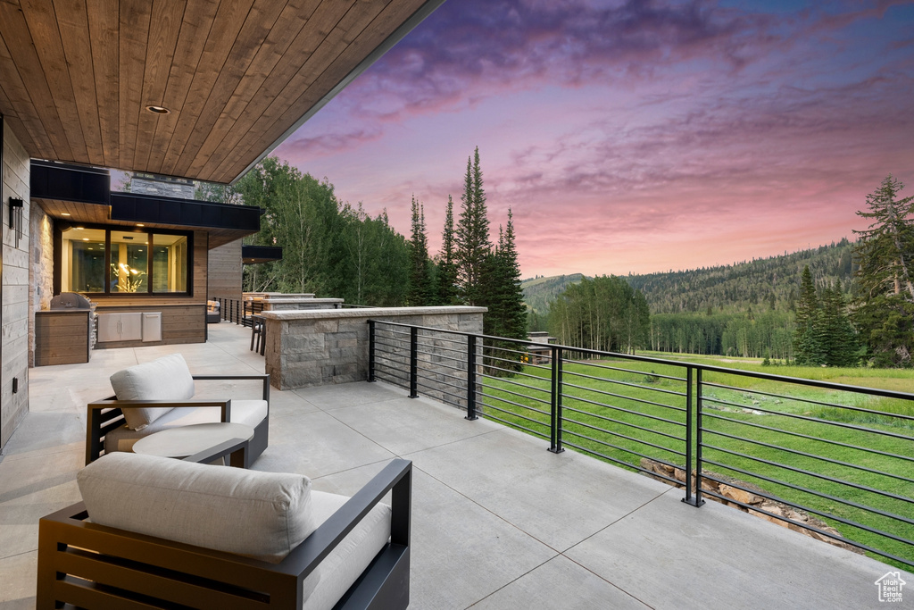 Patio terrace at dusk featuring a yard and a balcony