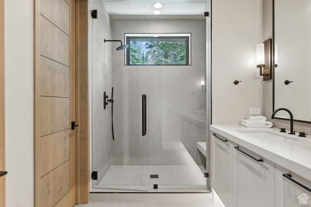 Bathroom featuring a shower with shower door and vanity