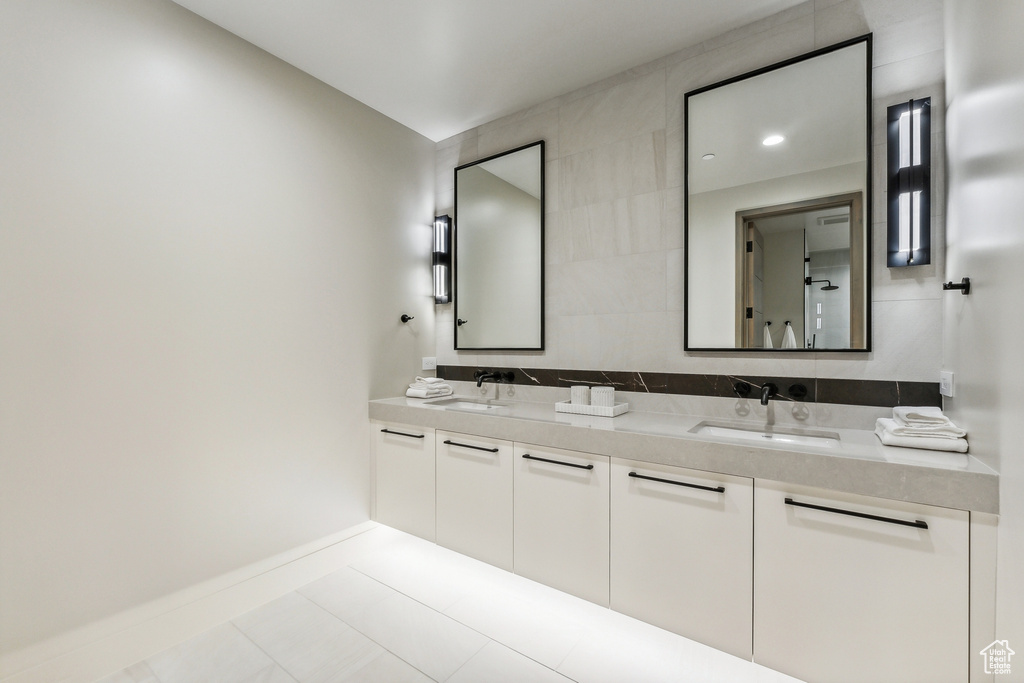 Bathroom with tile patterned floors, tile walls, and dual bowl vanity