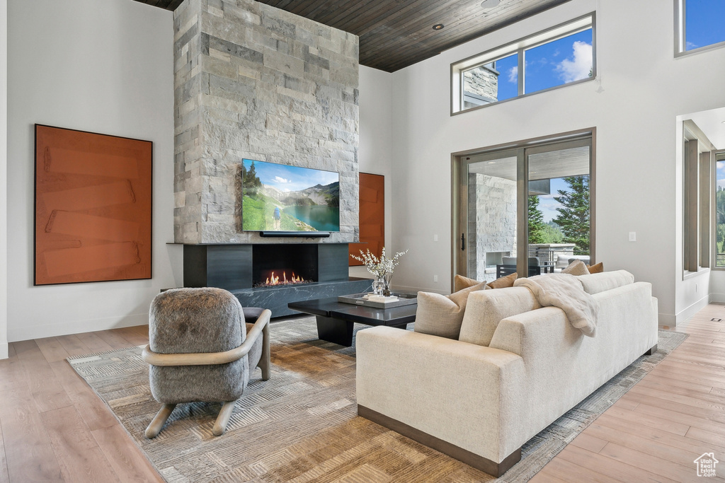 Living room with a fireplace, wooden ceiling, light hardwood / wood-style floors, and a towering ceiling