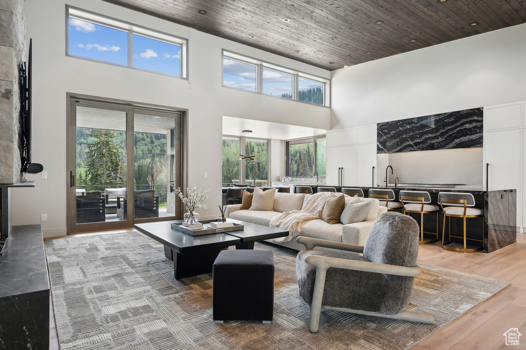 Living room featuring a towering ceiling, wood ceiling, and plenty of natural light