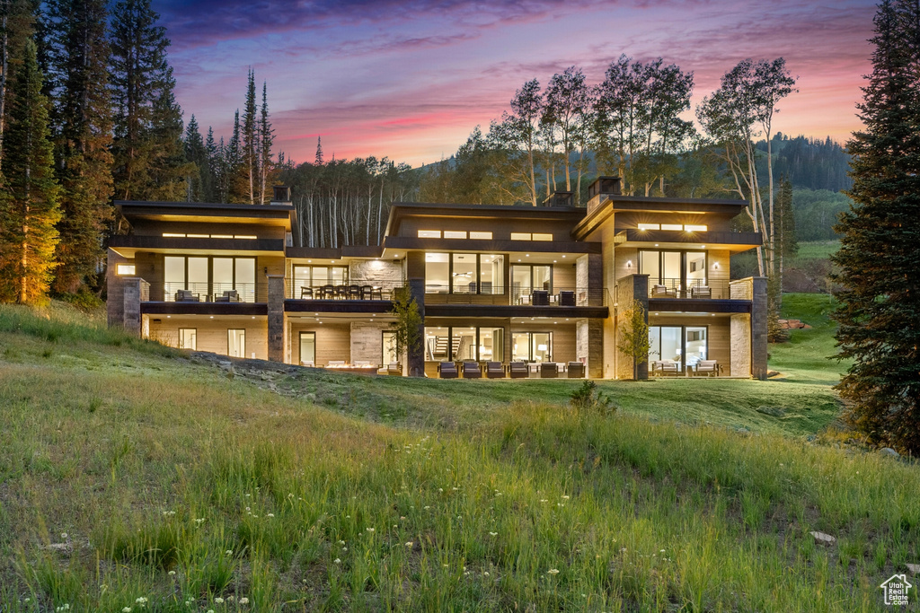 Back house at dusk featuring a balcony