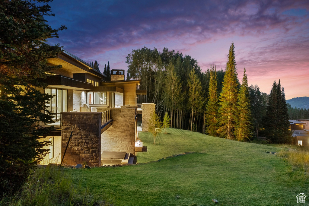 Property exterior at dusk featuring a lawn