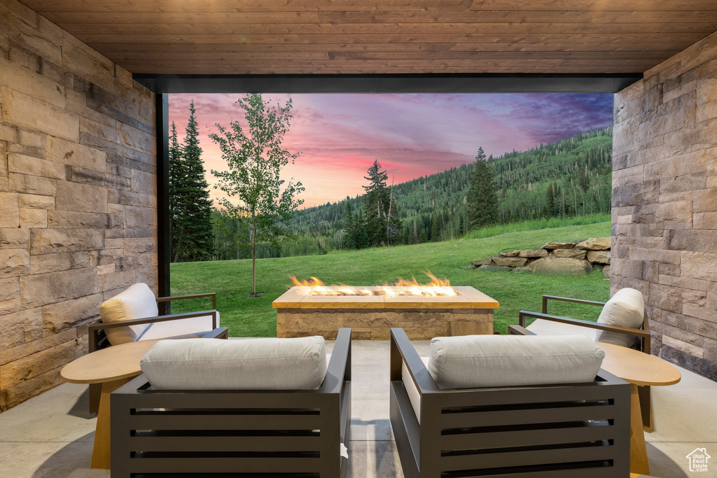 Patio terrace at dusk featuring an outdoor living space with a fire pit and a lawn