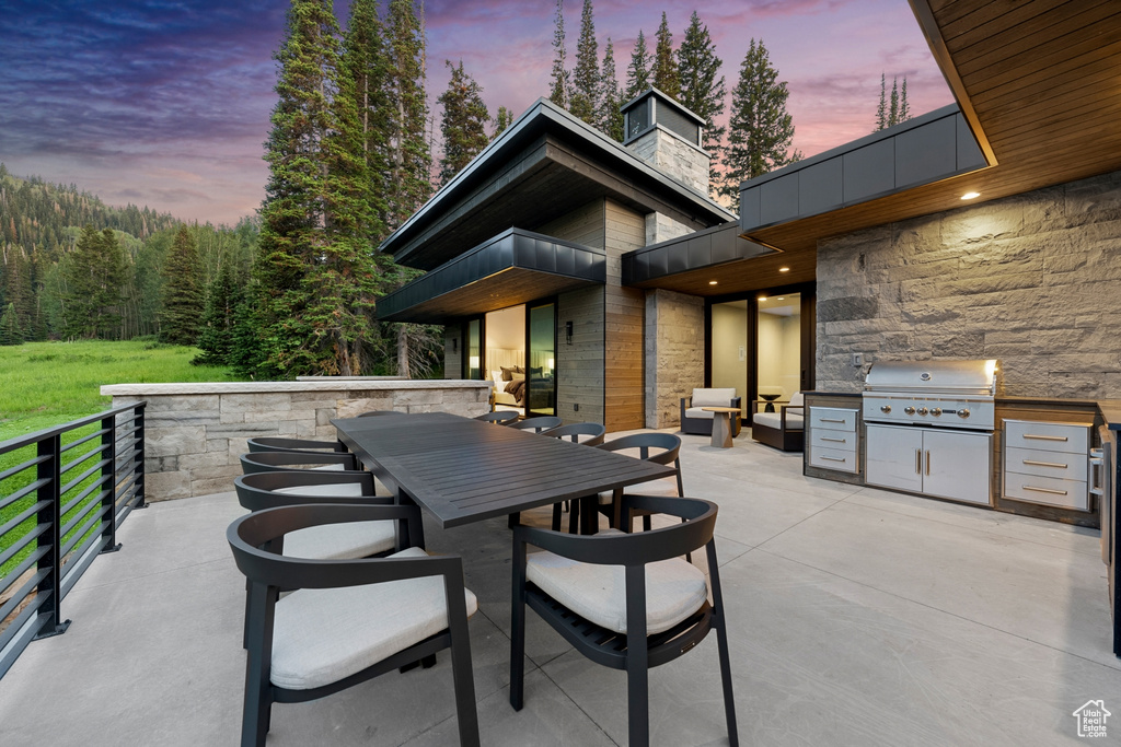 Patio terrace at dusk featuring exterior kitchen and grilling area