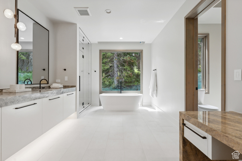 Bathroom with a tub, vanity, tile patterned floors, and toilet