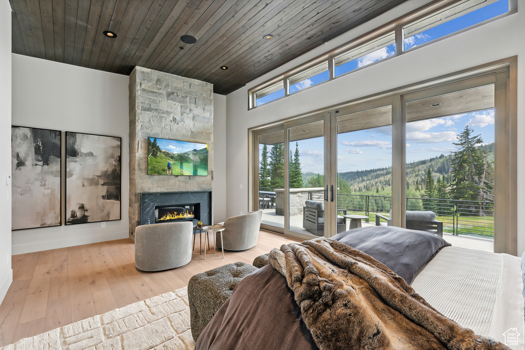 Bedroom featuring wood ceiling, a fireplace, access to outside, and light wood-type flooring