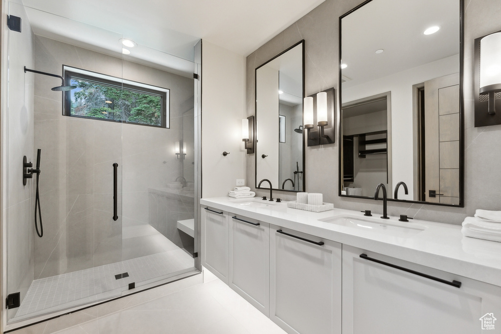 Bathroom with tile patterned floors, a shower with door, and double vanity