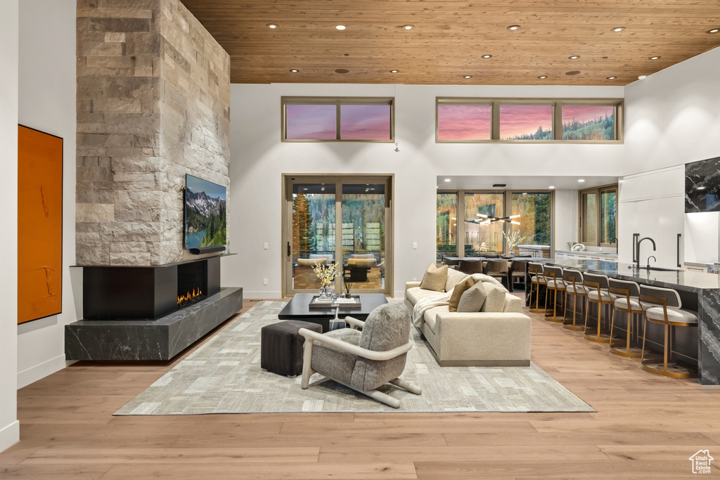 Living room with light hardwood / wood-style flooring, a multi sided fireplace, a towering ceiling, and wood ceiling