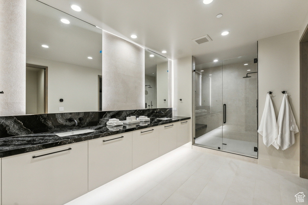 Bathroom featuring dual vanity, an enclosed shower, and tile patterned floors