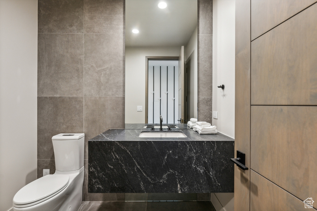 Bathroom featuring vanity, tile walls, toilet, and tile patterned flooring