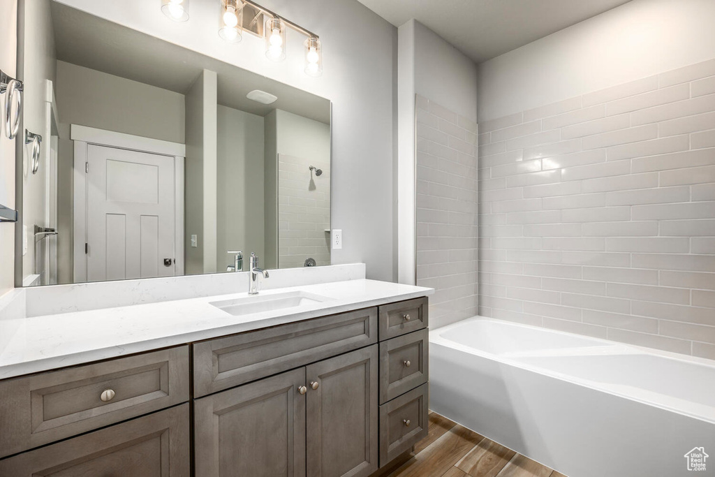 Bathroom featuring tub / shower combination, vanity, and hardwood / wood-style floors