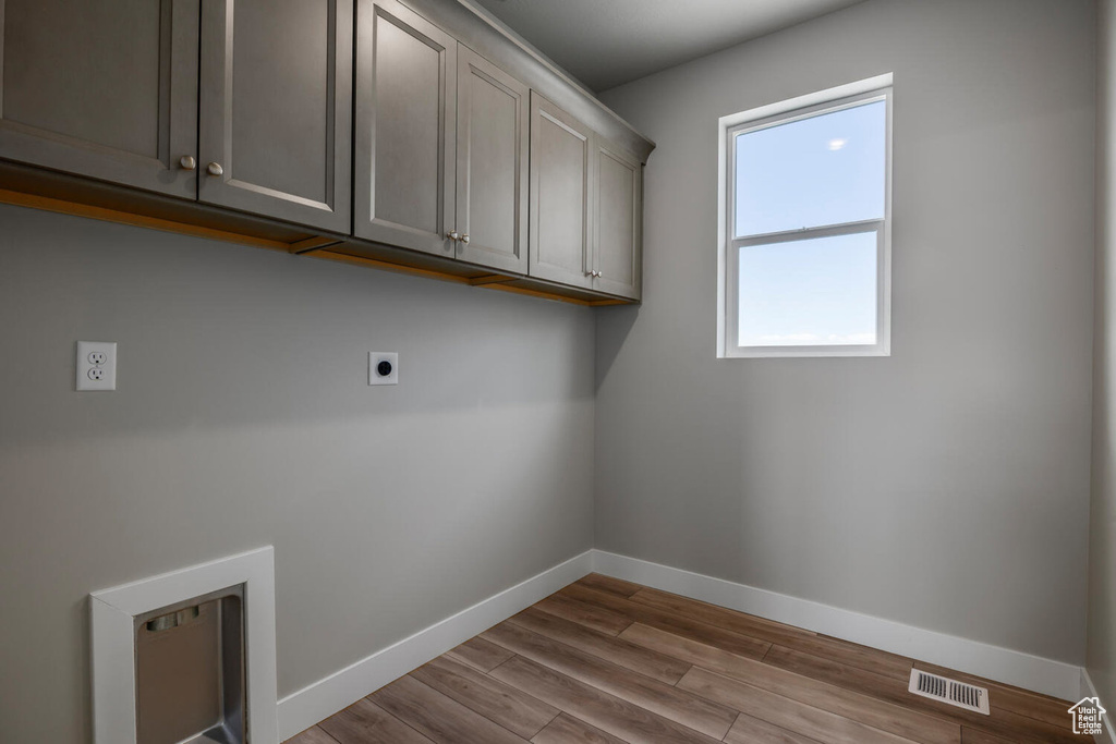 Washroom with cabinets, light hardwood / wood-style floors, hookup for an electric dryer, and a wealth of natural light