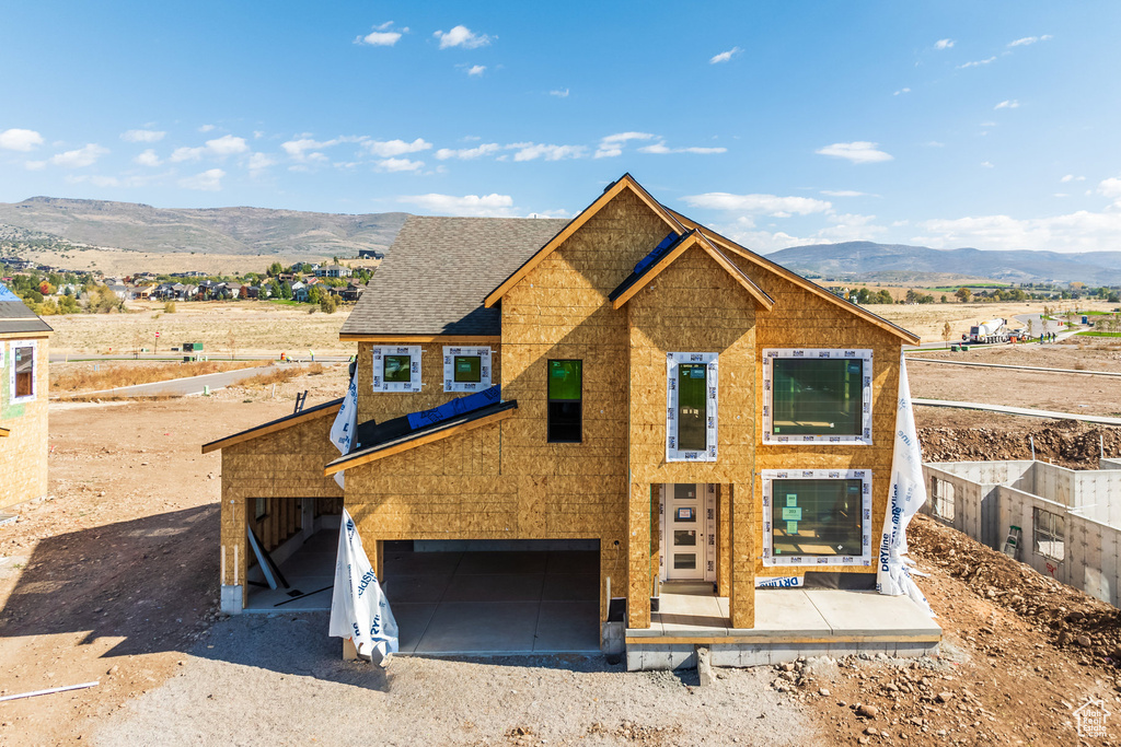 Unfinished property with a garage and a mountain view