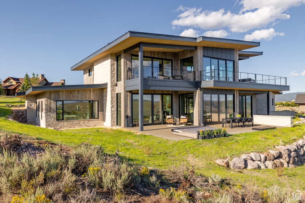 Back of house featuring a balcony, a patio, and a yard