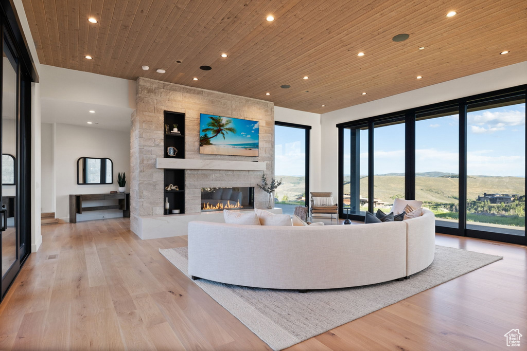 Living room featuring light hardwood / wood-style floors, wood ceiling, and a stone fireplace