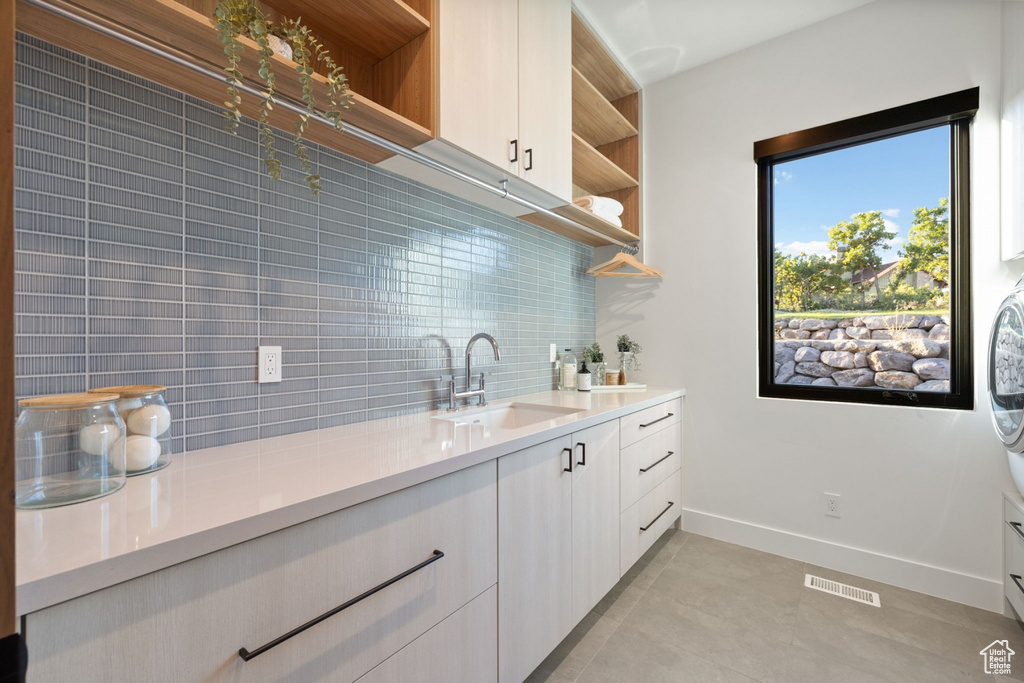 Kitchen featuring light tile patterned flooring, sink, and decorative backsplash