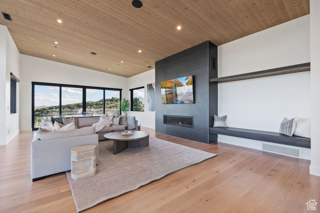 Living room with wood ceiling, high vaulted ceiling, light hardwood / wood-style floors, and a fireplace