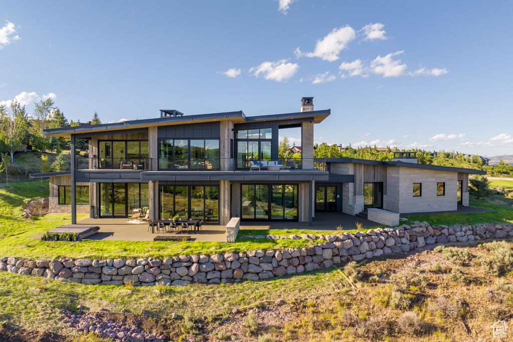 Rear view of house featuring a patio area, a yard, and a balcony