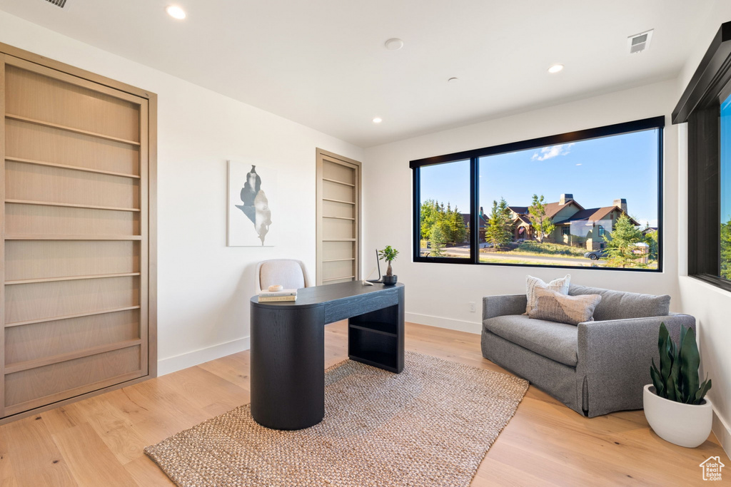 Office with built in shelves and light hardwood / wood-style floors