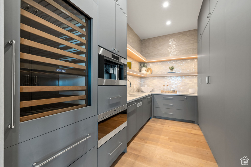 Interior space featuring backsplash, light hardwood / wood-style floors, gray cabinets, and sink