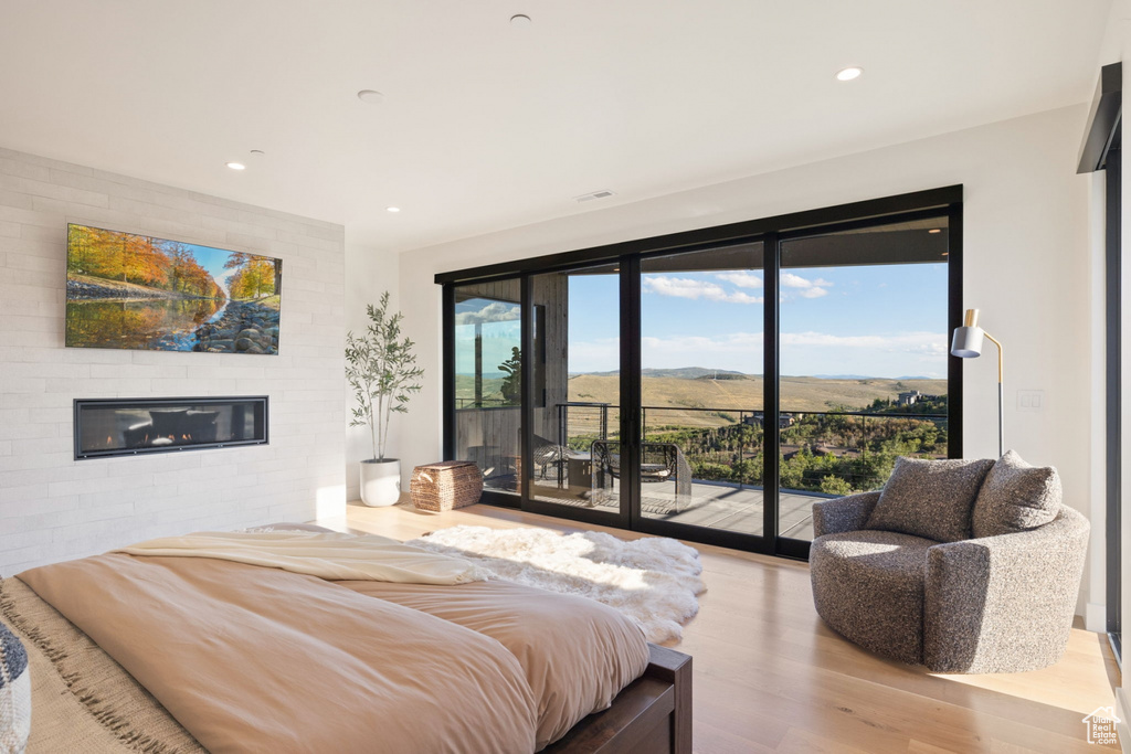 Bedroom with light hardwood / wood-style flooring, access to exterior, and brick wall